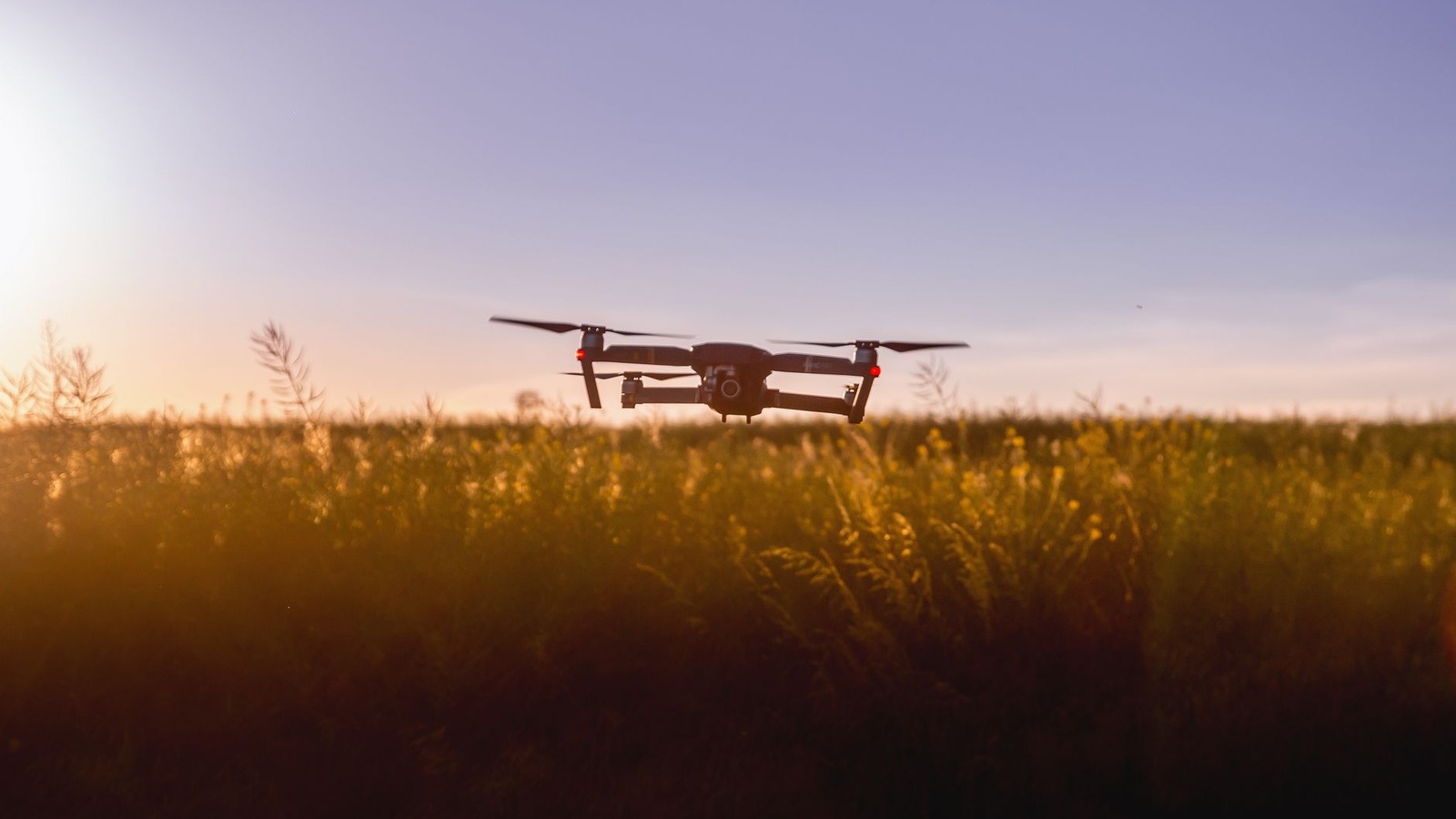 Un drone en vol au crépuscule au-dessus d'un champ