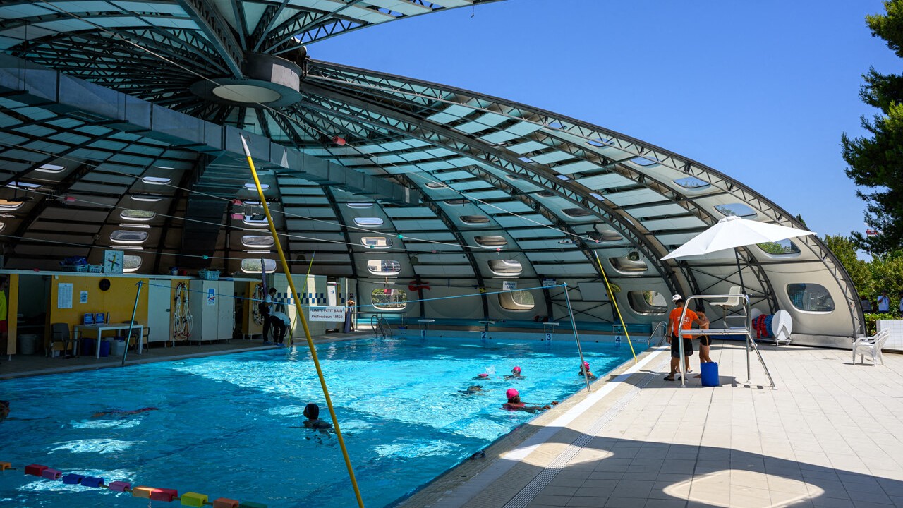 Des enfants nagent sous la coupole de la piscine Jean Vivès à Montpellier pendant un stage Été Quartier