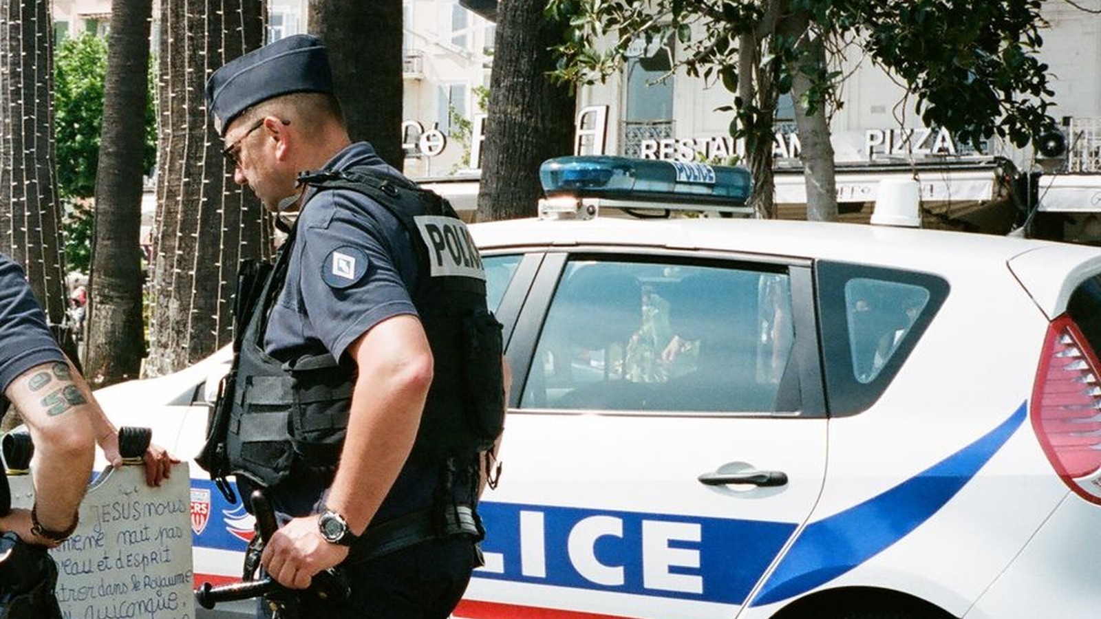 Un policier de la police nationale près d'un véhicule sérigraphié POLICE dans une rue du sud de la France