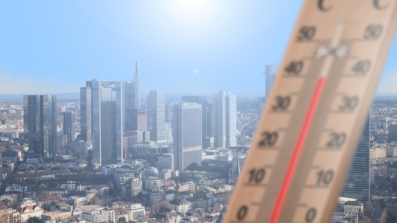 Thermomètre affichant près de 40 °C sous un soleil de plomb au-dessus d'une ville en pleine canicule