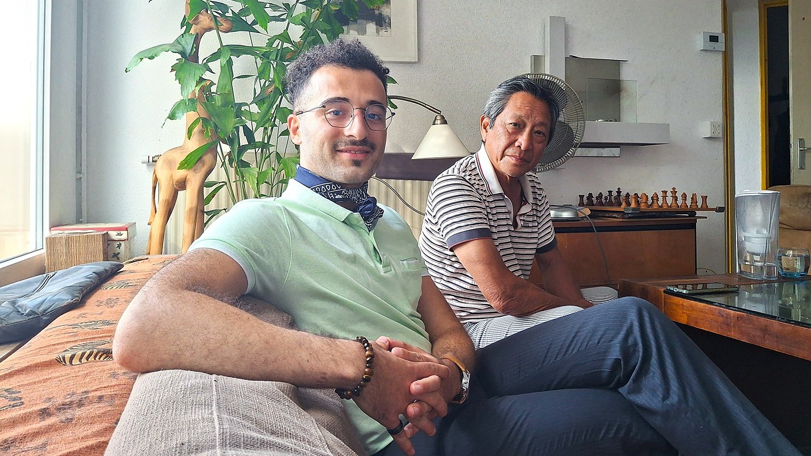 Un étudiant et un retraité assis dans le salon de leur appartement à Montpellier