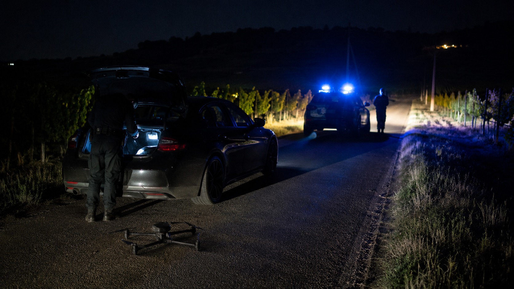 Contrôle routier de nuit par des gendarmes, un drone posé sur la route près d'une voiture