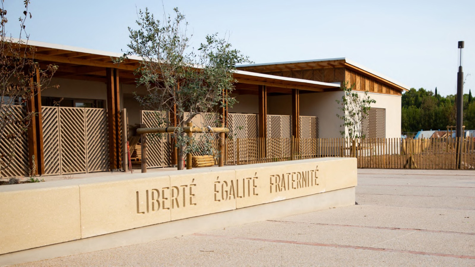 Façade en bois de la nouvelle école Léontine-Olivier à Jacou, avec la devise Liberté Égalité Fraternité gravée sur le muret du parvis