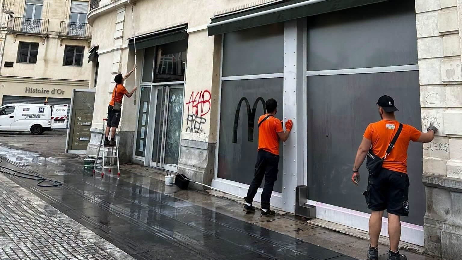 Nettoyage des tags sur la devanture barricadée d'un commerce du centre de Montpellier